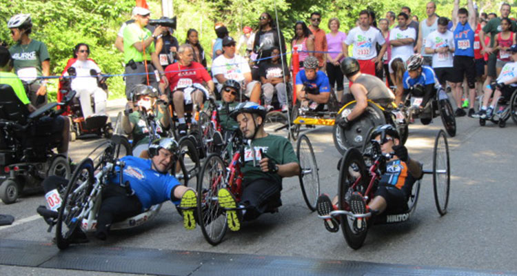 Three men on wheelchair bikes in race